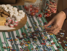 Family holiday ideas, Two hands jigsaw puzzle with festive treats like shortbread, chocolate chip cookies, peppermint candies, marshmallows, candy canes and Lindt truffles.