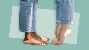 Two people standing barefoot on a green background, with feet positioned close together.